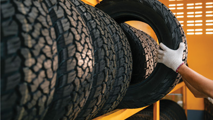 Someone taking a tyre from a rack of tyres. 