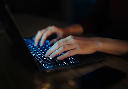 Hands typing on a laptop keyboard. 