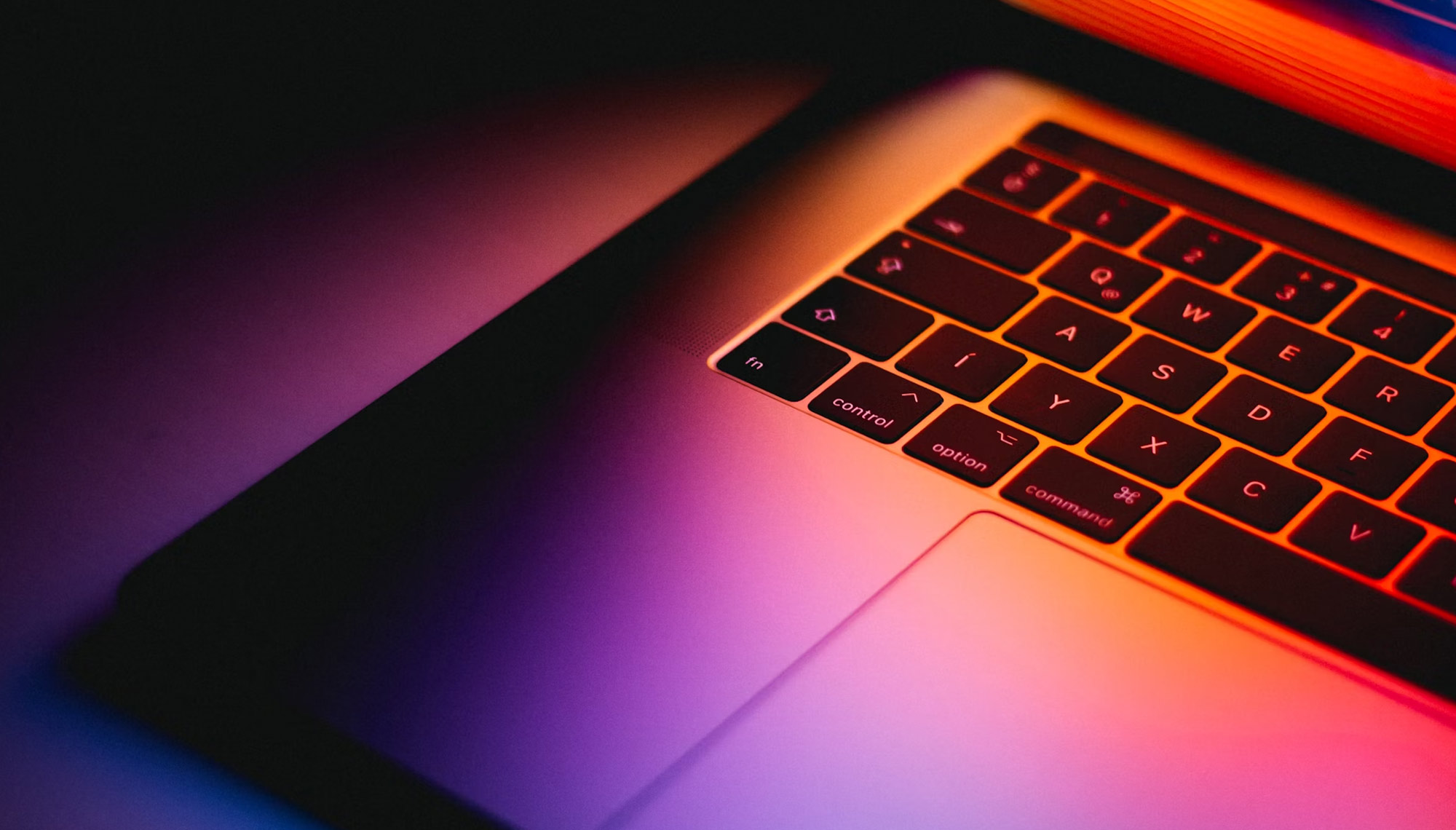 Close-up of a laptop keyboard illuminated by colorful lighting